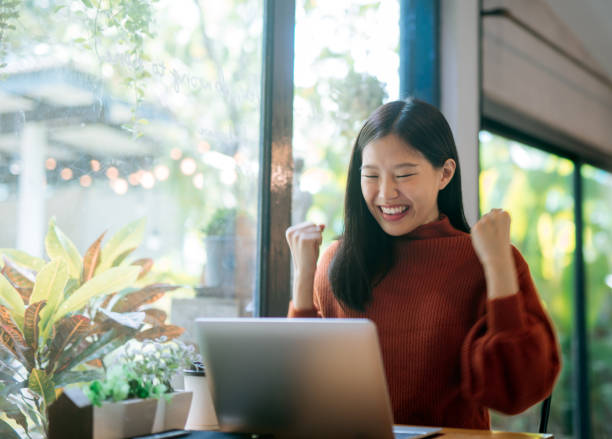 la giovane ragazza asiatica celebra il successo o la posa felice con il laptop - businesswoman business cheering women foto e immagini stock