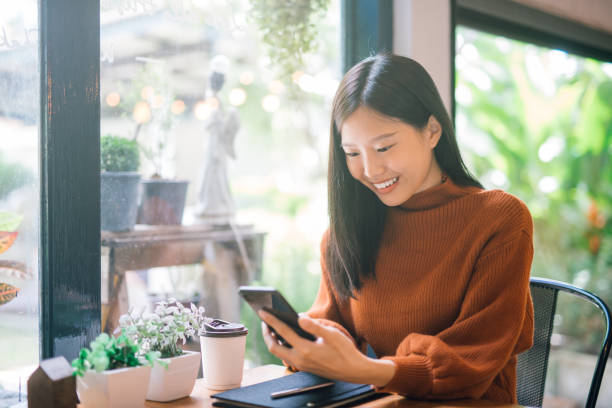 Young Asian woman using phone Young Asian woman using phone at a coffee shop happy and smile. korean ethnicity photos stock pictures, royalty-free photos & images