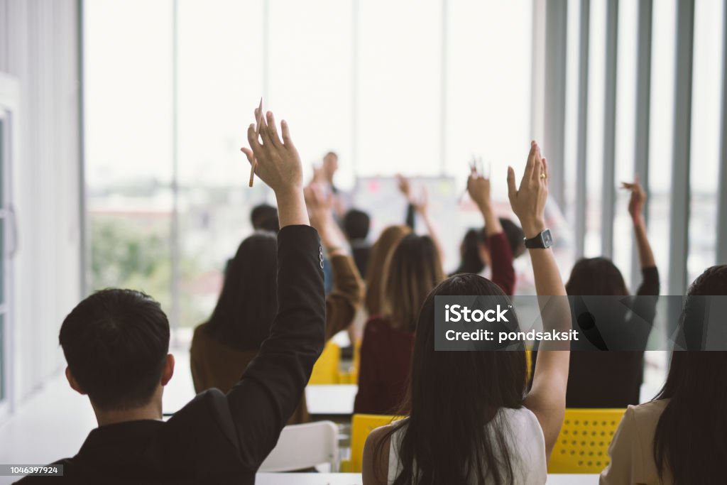 asking in seminar class room at Conference Raised up hands and arms of large group in seminar class room at Conference Hand Raised Stock Photo