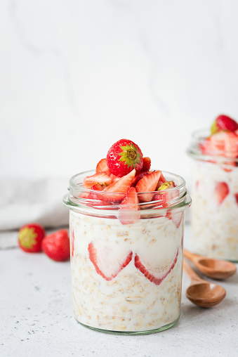 Healthy breakfast overnight oats with strawberries and bamboo wooden spoons for eating. Vegan, vegetarian breakfast