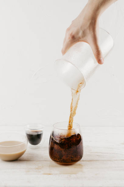 istock Woman's hand pouring freshly brewed coffee into glass cup on wooden table, selective focus 1046407262