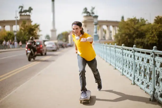 Young man in yellow t-shirt skateboarding in the city