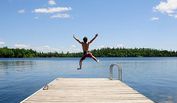 istock Young man jumps off dock on beautiful summer's day. 104641431