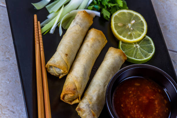 istock Oriental, Plate with spring rolls chop sticks, three spring rolls, spring onions, lime, lemon, sweet chilli sauce. 1046415412