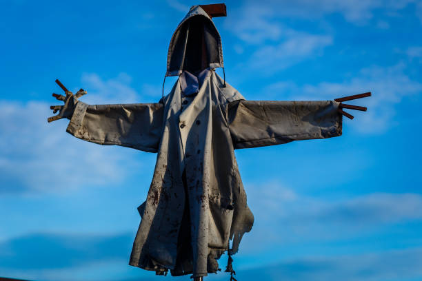 scary scarecrow hooded against the blue sky
