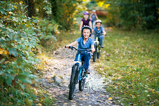Little boy and his family riding bicycles in nature. The boy is smiling happily.\nNikon D810