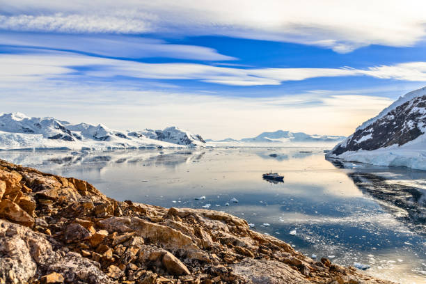 Antarctic mountain landscape with cruise ship standing still in Antarctic cruise ship among icebergs and Gentoo penguins gathered on the shore of Neco bay, Antarctica antartica stock pictures, royalty-free photos & images