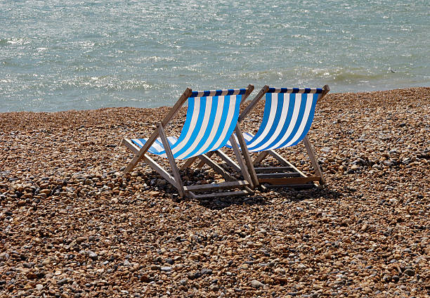 Deckchairs on pebble beach stock photo