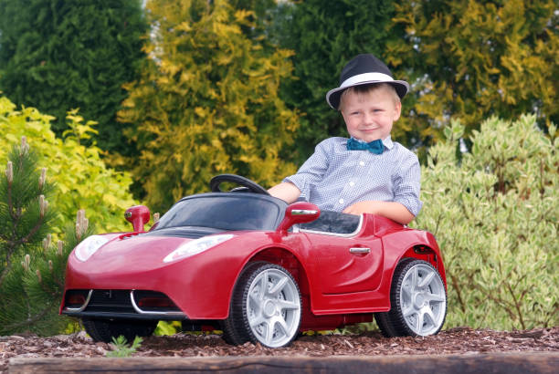 A young boss in the car Three-year boy in a hat sits in a red toy car kid toy car stock pictures, royalty-free photos & images