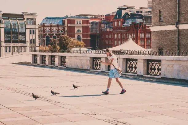 Photo of A teenaged girl shooting pigeons with her smartphone on Patriarshy bridge in Moscow, Russia