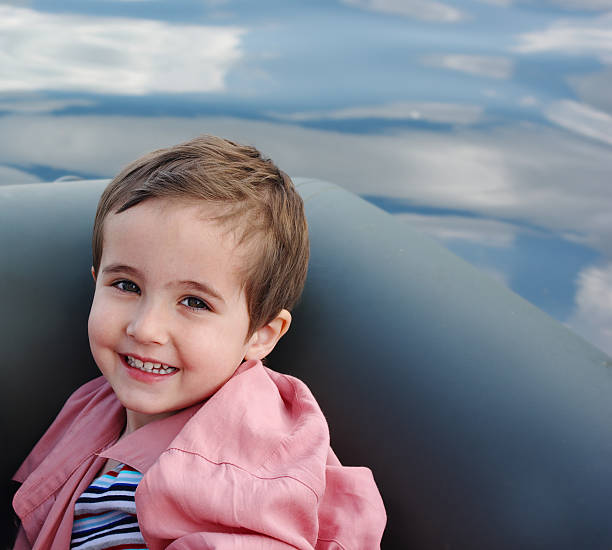 istock Little boy on boat with clouds reflected in the river 104643939