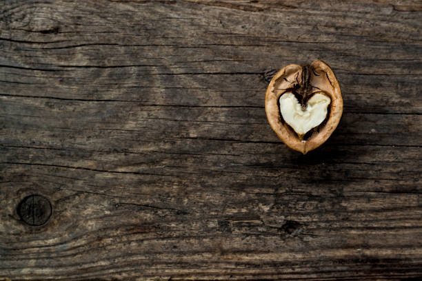 Walnut heart shaped on wooden background with copy space for design or text.