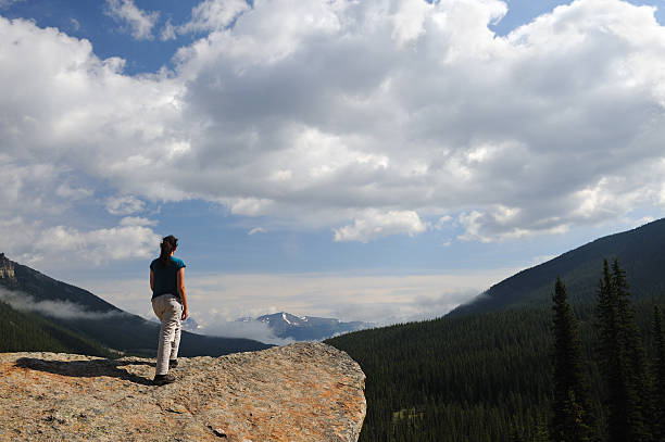 istock Hiker Standing at Cliff Edge Overlooking Mountain Valley 104644547
