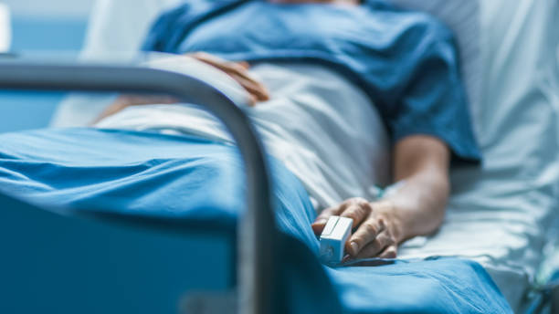im krankenhaus schläft kranker männlicher patient auf dem bett. heart rate monitor ausrüstung ist an seinem finger. - heilbehandlung stock-fotos und bilder