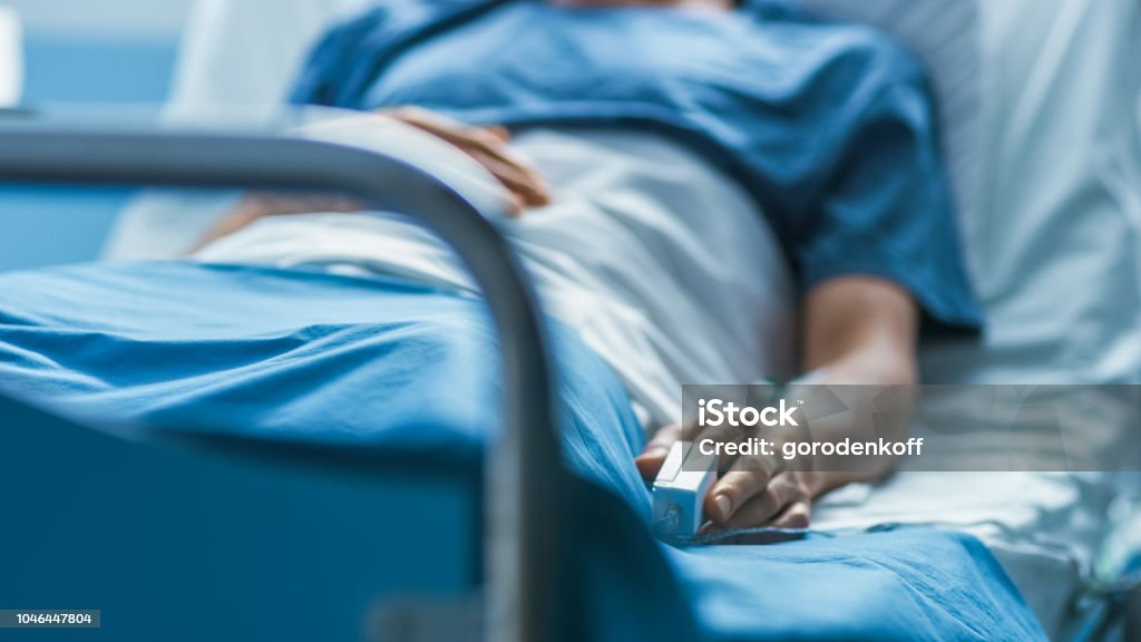 No Hospital, paciente do sexo masculino doente dorme na cama. Equipamentos de Monitor de frequência cardíaca é no seu dedo. - Foto de stock de Hospital royalty-free