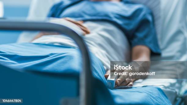 Foto de No Hospital Paciente Do Sexo Masculino Doente Dorme Na Cama Equipamentos De Monitor De Frequência Cardíaca É No Seu Dedo e mais fotos de stock de Hospital