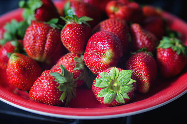 Ripe strawberries on a red plate.