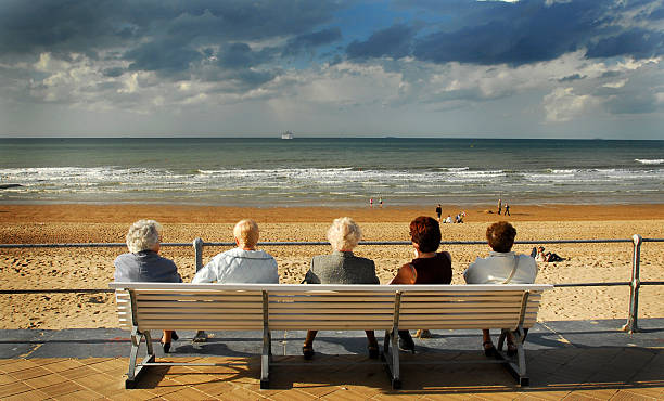 Five Old ladies sitting on bench chilling out near sea stock photo