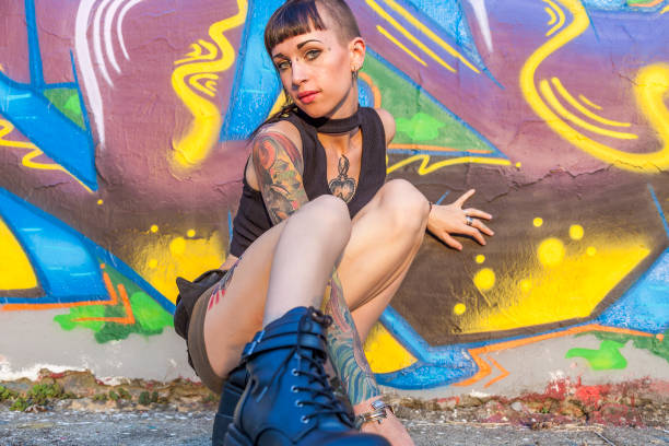 tattooed rebel girl posing against a wall