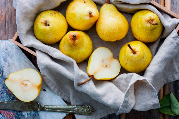 chopped fresh yellow pear on a wooden board, top view, selective focus fruit background. - pera imagens e fotografias de stock
