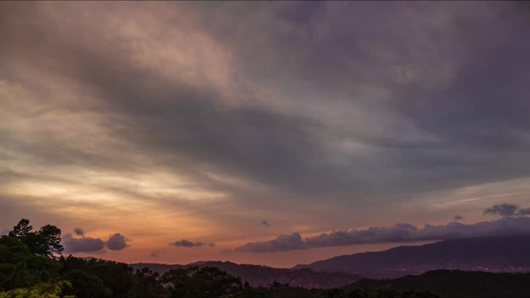 Time lapse of a day to night sequence with clouds moving fast and sun rays glowing onto the high clouds.