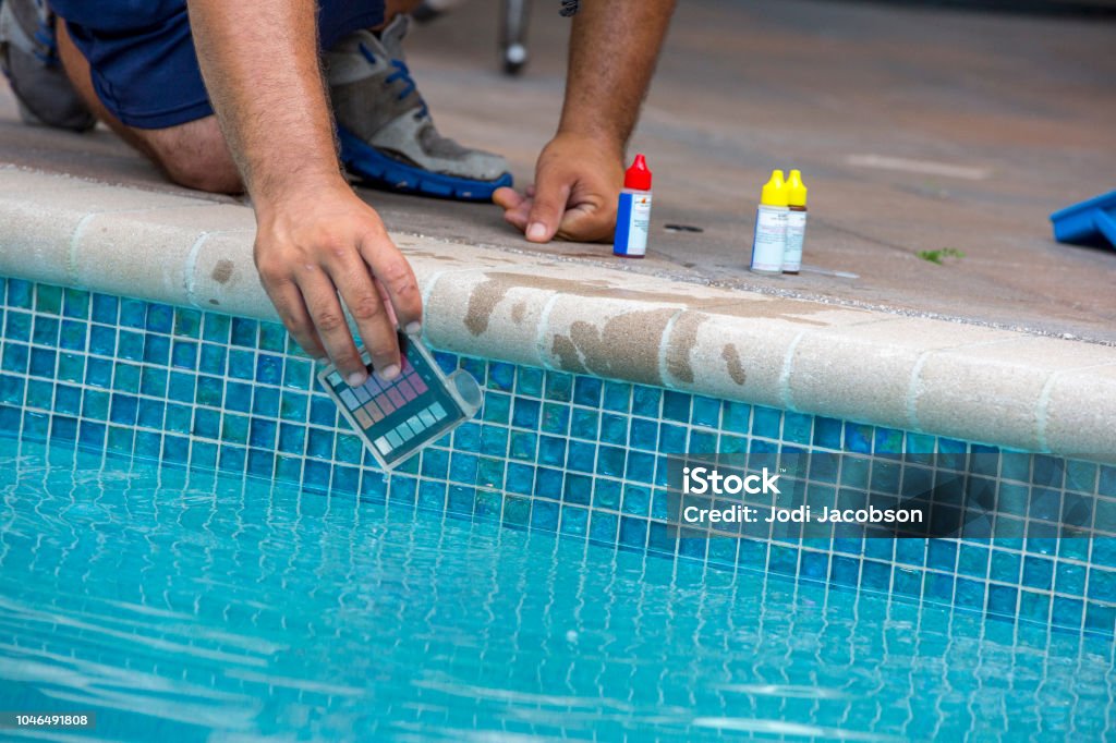Pool testing kit being used in a swimming pool An unrecognizable man is using a pool testing kit to test the chemical levels in a   swimming pool. This is a standard kit used by pool maintenance people and homeowners to test the water to keep it healthy for swimmers. Shot with Canon 5D Mark lll. Swimming Pool Stock Photo