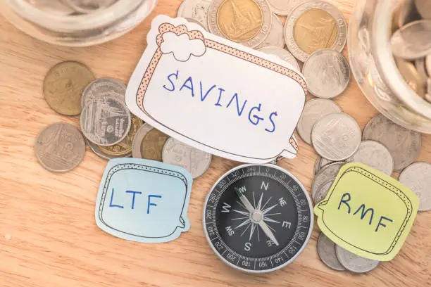 compass and coins on money of business planning and finance and savings. LTF and RMF concept.