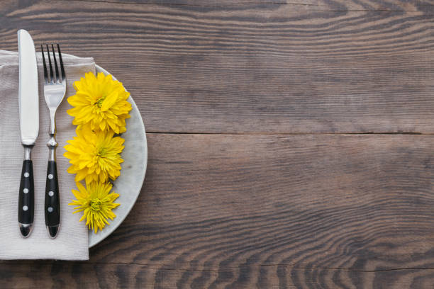 istock Rustic table setting with linen napkin, cutlery, ceramic plates, yellow glasses and yellow flowers 1046510824