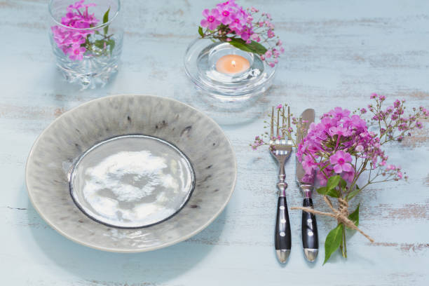 istock Rustic table setting with pink flowers and candle on light wooden table. 1046511146