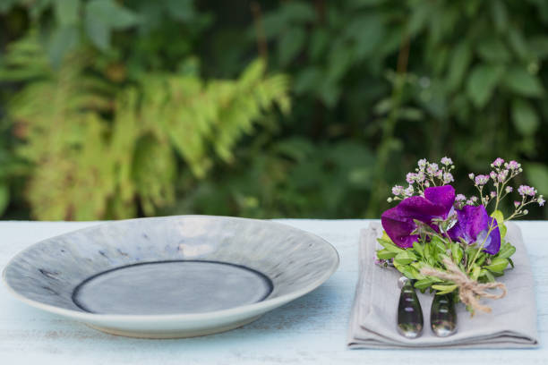 Rustic table setting with purple flowers on light wooden table.