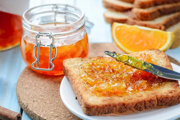 Slices of toasted bread with orange jam and glass jar for breakfast