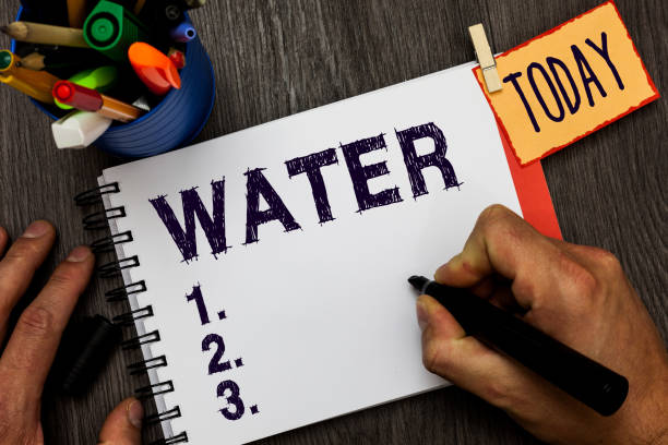 istock Handwriting text Water. Concept meaning colourless transparent odourless liquid which forms seas rivers Man holding marker notebook clothespin hold reminder cup markers wood table. 1046534024