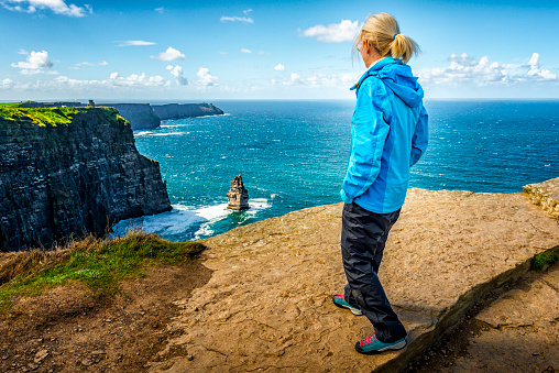 woman looking down to Cliffs of Moher in Ireland