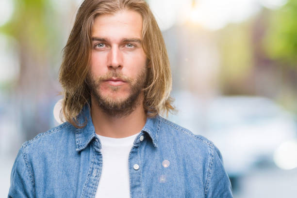istock Young handsome man with long hair over isolated background with serious expression on face. Simple and natural looking at the camera. 1046559804