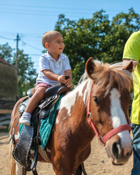 niño, tomar un paseo en pony - horse child animal feeding fotografías e imágenes de stock
