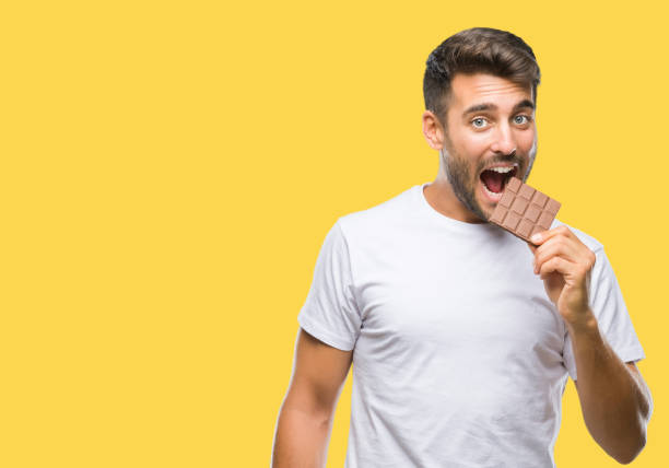 istock Young handsome man eating chocolate bar over isolated background with a confident expression on smart face thinking serious 1046566256