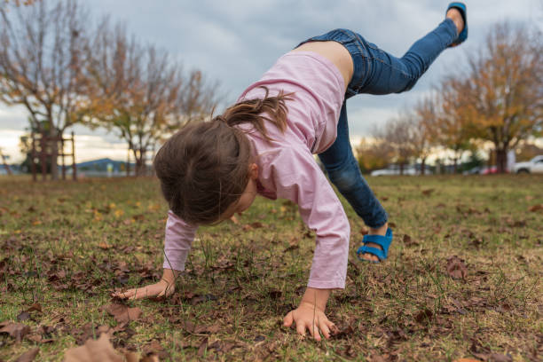 istock Full Length Of Girl Practicing Handstand On Playing Field 1046571286