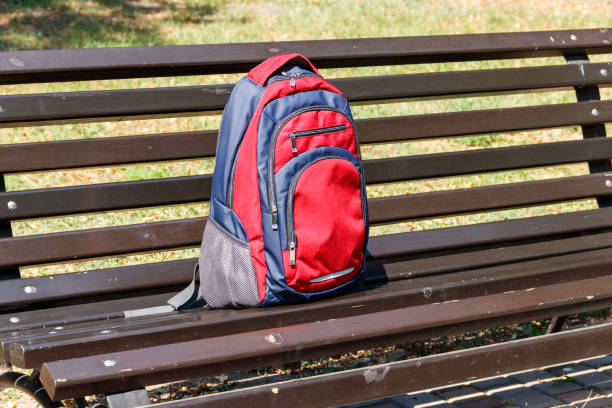 istock Backpack on wooden bench in city park 1046577976