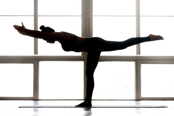 Young sporty attractive woman practicing yoga, doing Warrior Three Young sporty attractive woman practicing yoga, doing Warrior III, exercise, Virabhadrasana 3 pose, working out, wearing sportswear, indoor full length, at yoga studio, side view silhouette pilates stick exercise stock pictures, royalty-free photos & images