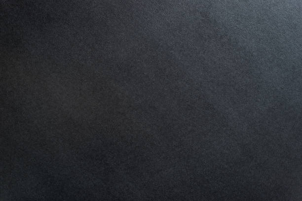 istock Black textured background lit with dim light from the right. 1046582236
