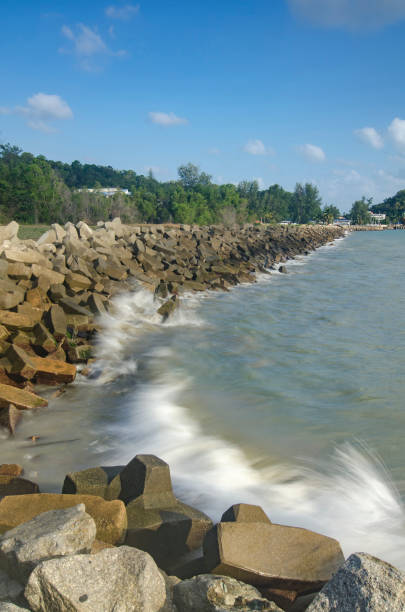 istock wave crushing concrete breakwater on the beach over blue sky background at sunny day 1046583062