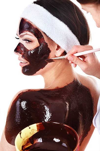 красивая девушка с шоколадная маска для лица применяются косметолог,. - massaging chocolate spa treatment body стоковые фото и изображения