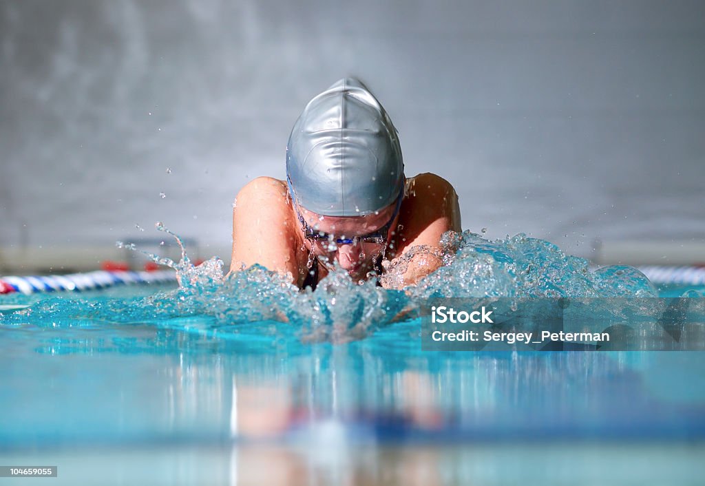 Female swimmer with gray cap doing breaststroke woman swims using the breaststroke in indoor pool Swimming Stock Photo