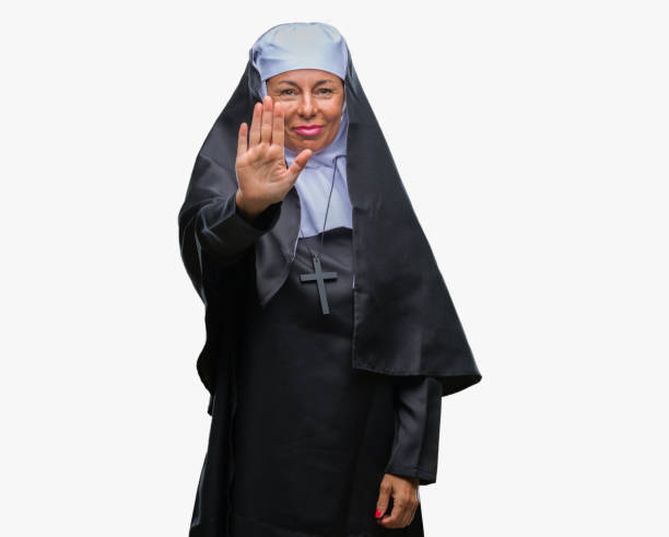 mulher de meia idade sênior freira católica cristã sobre fundo isolado fazendo parar de cantar com a palma da mão. expressão de aviso com gesto negativo e grave na face. - nun sign holding women - fotografias e filmes do acervo