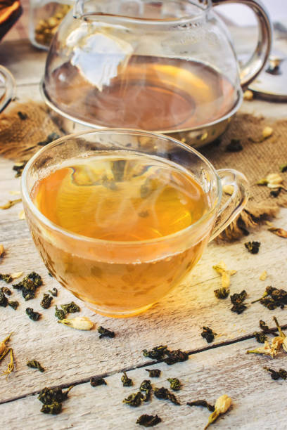 istock Green tea with Jasmine and black with transparent lemon in a small Cup on a light background. The tea maker. Selective focus. 1046599384