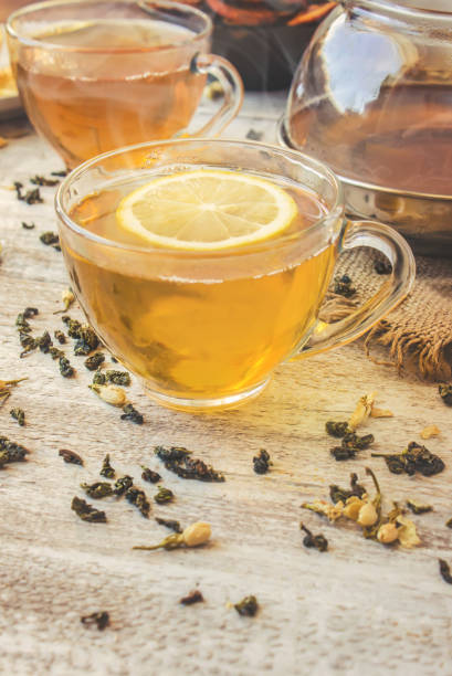 istock Green tea with Jasmine and black with transparent lemon in a small Cup on a light background. The tea maker. Selective focus. 1046599414