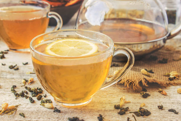 istock Green tea with Jasmine and black with transparent lemon in a small Cup on a light background. The tea maker. Selective focus. 1046599420