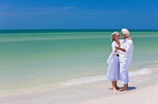 A pair of blue beach chairs with umbrellas sitting on white sandy beaches in front of the ocean on a sunny day.