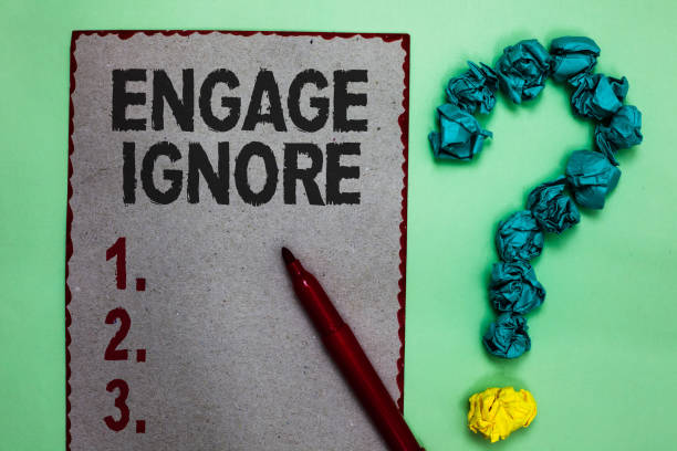 istock Handwriting text writing Engage Ignore. Concept meaning Silent Treatment Manipulative Punishment Sulking Shunning Gray paper marker crumpled papers forming question mark green background. 1046618714