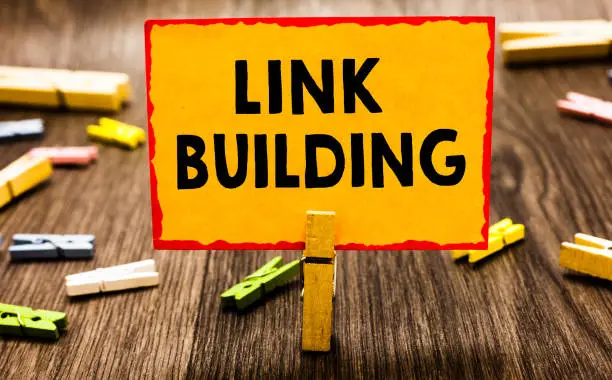 Photo of Conceptual hand writing showing Link Building. Business photo showcasing SEO Term Exchange Links Acquire Hyperlinks Indexed Clothespin holding orange paper note clothespin wooden floor.